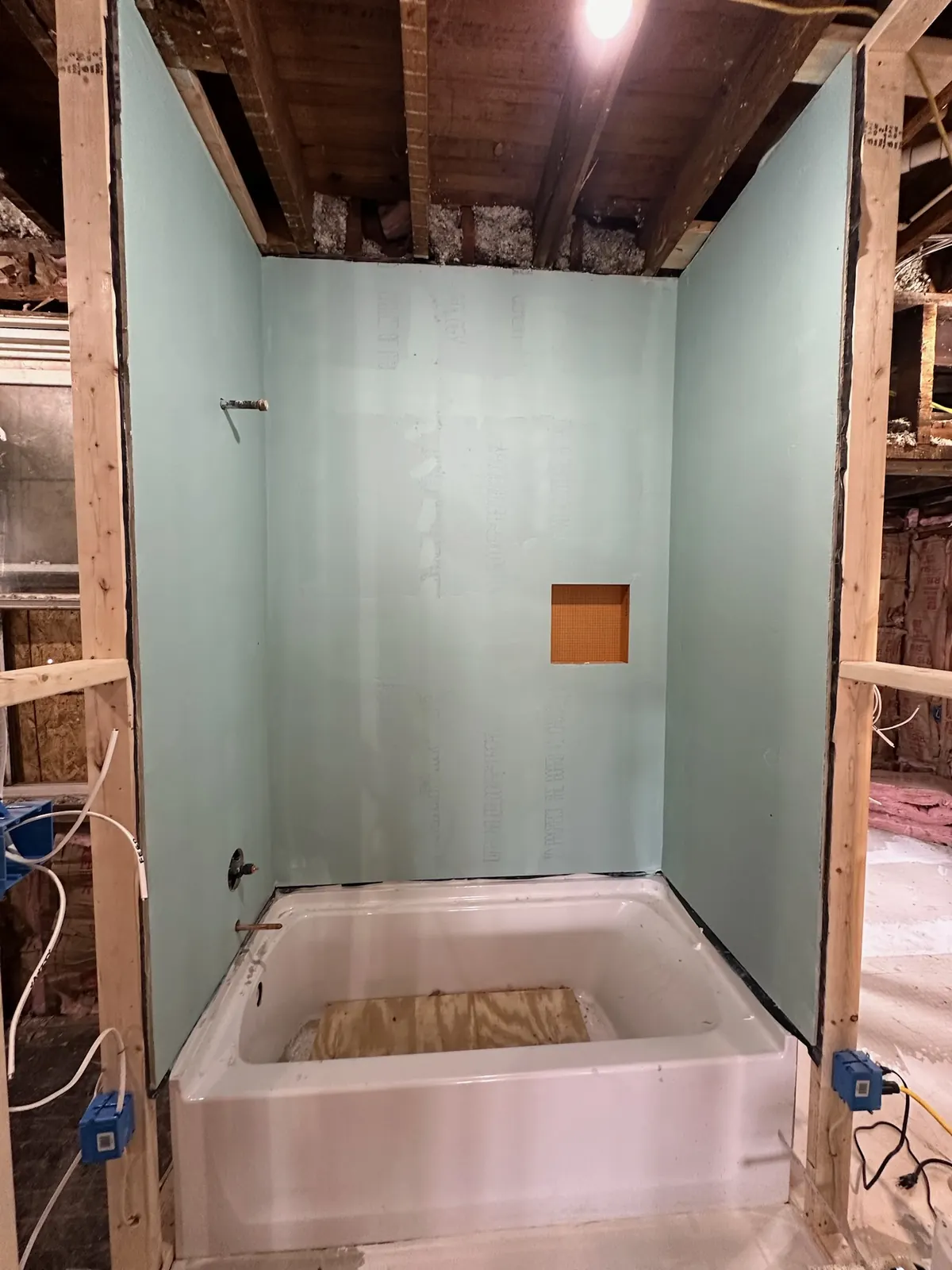 Bathroom tub and wall panels being installed during construction