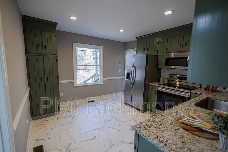 Completed Kingsland Rd kitchen with green cabinetry and marble-look counters