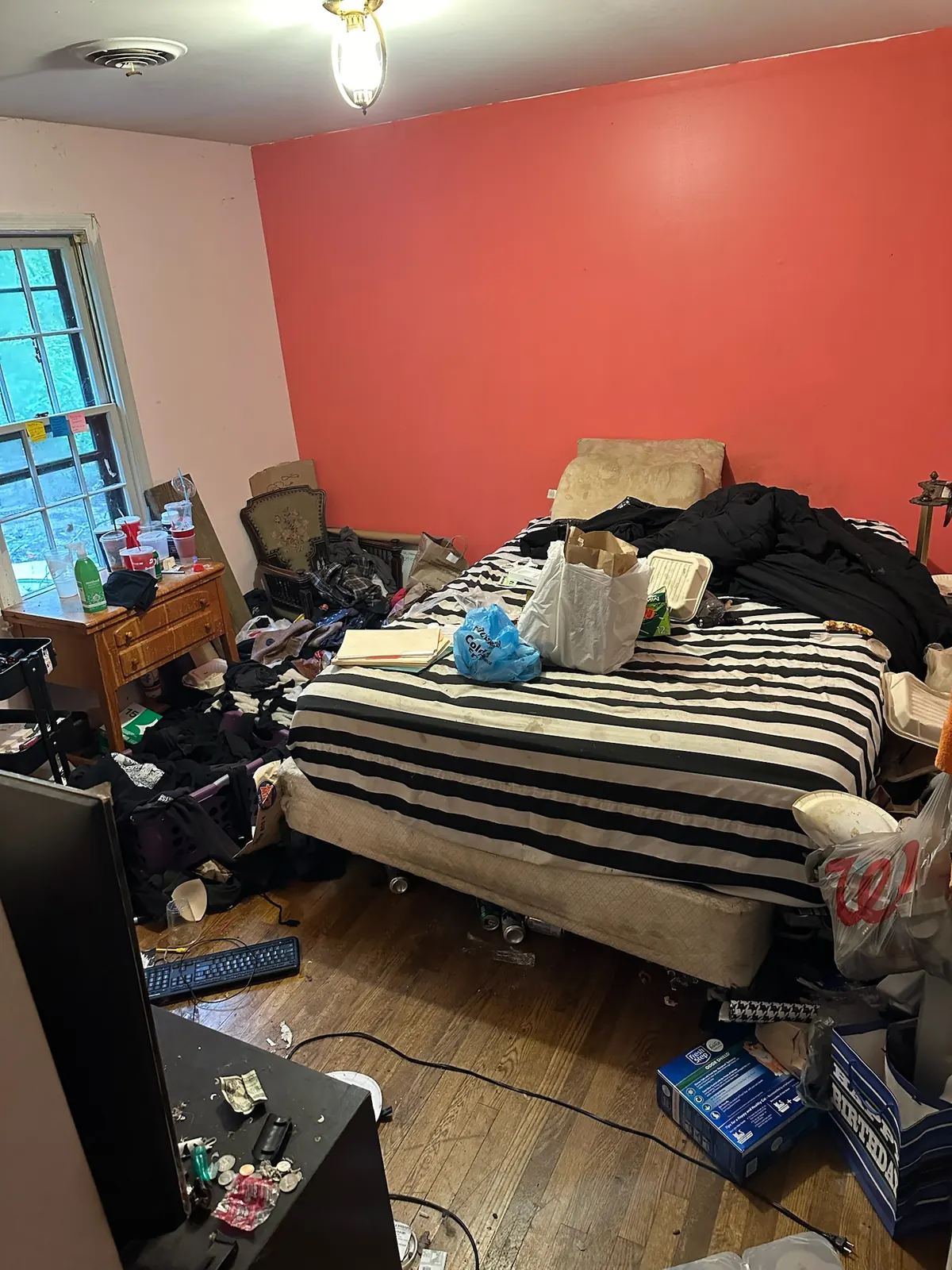 Cluttered bedroom at Kingsland Rd before renovation with a coral accent wall