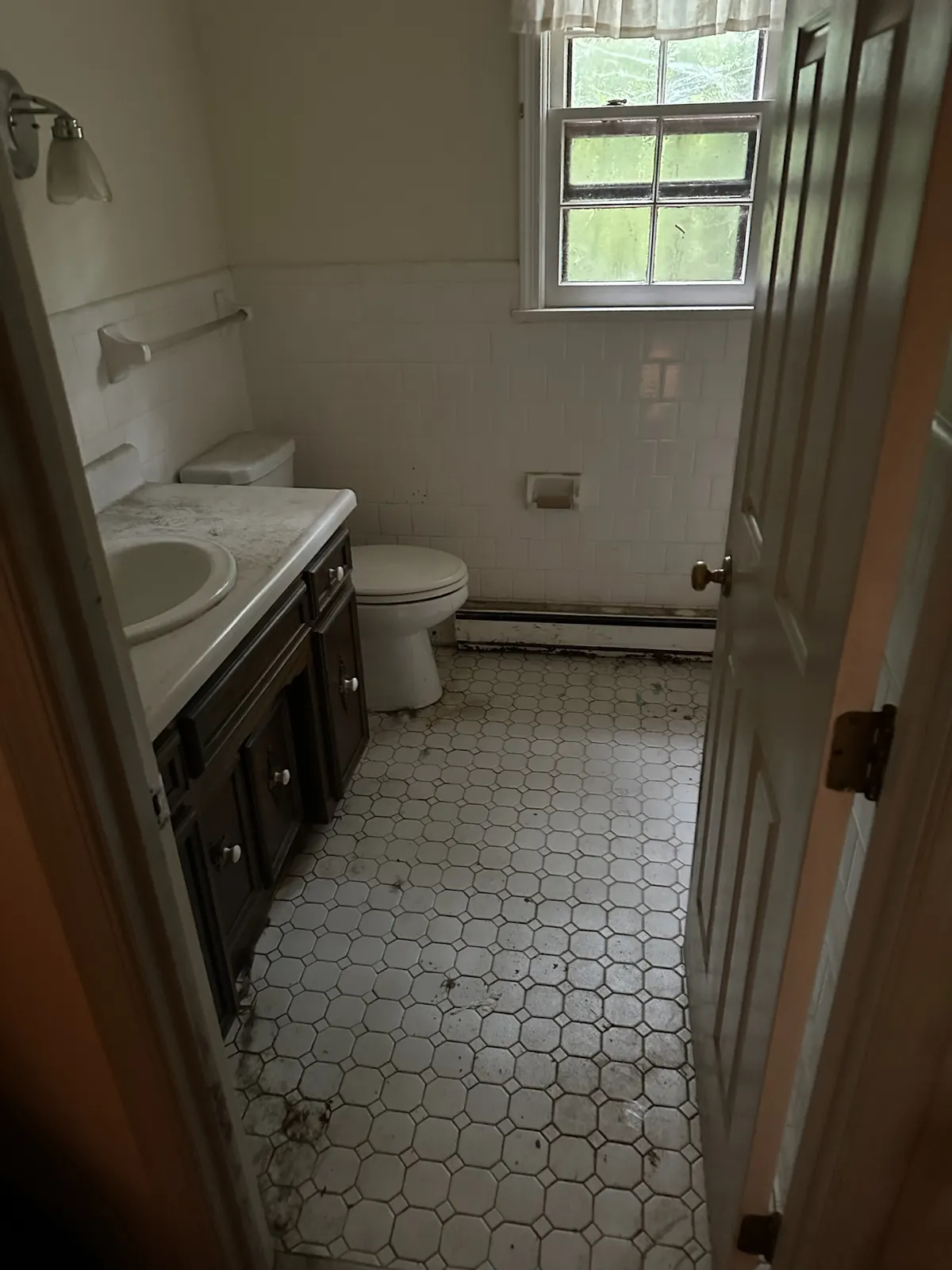 Dated hall bathroom at Kingsland Rd before renovation with worn hex tile floor and dark vanity